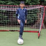 boy leaning his foot on a ball